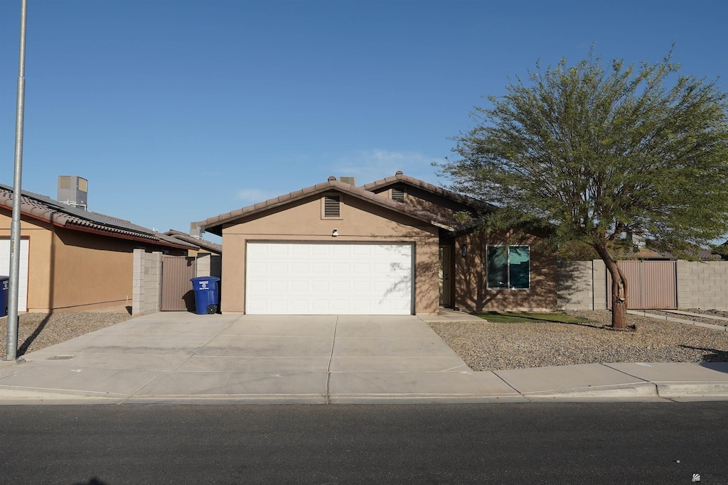 view of front of property featuring stucco siding, driveway, an attached garage, and fence