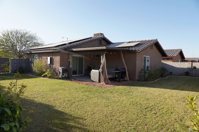 rear view of property featuring a tile roof, stucco siding, a fenced backyard, a yard, and a patio