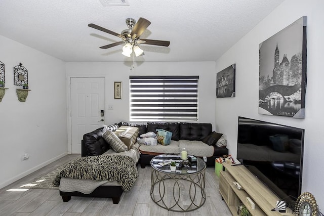 living room with baseboards, a textured ceiling, a ceiling fan, and wood finished floors