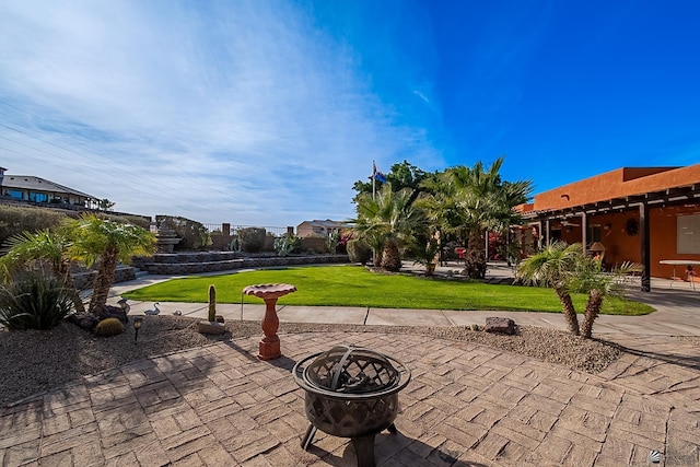 view of property's community with a patio area, an outdoor fire pit, and a yard