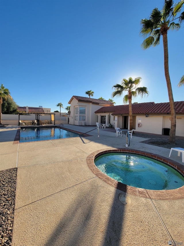 pool with a patio area and a hot tub