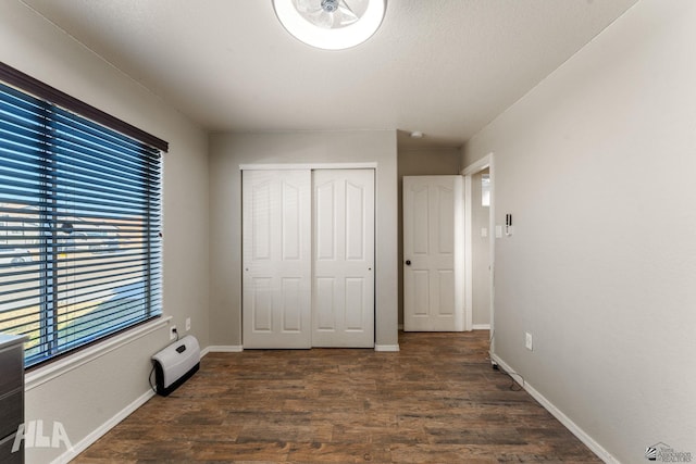 unfurnished bedroom with a closet, dark hardwood / wood-style floors, and a textured ceiling