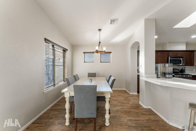 dining room with a notable chandelier, dark wood-type flooring, and vaulted ceiling