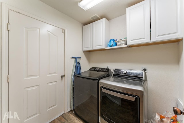 clothes washing area with cabinets, washing machine and dryer, and hardwood / wood-style floors