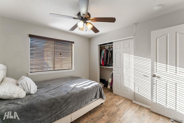 bedroom featuring multiple windows, hardwood / wood-style floors, ceiling fan, and a closet