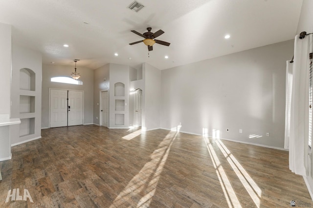 unfurnished living room featuring dark wood-type flooring, ceiling fan, and a towering ceiling