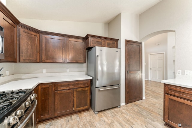 kitchen featuring vaulted ceiling, appliances with stainless steel finishes, and light hardwood / wood-style flooring