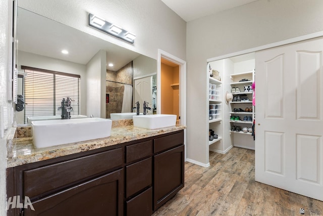 bathroom with hardwood / wood-style flooring, vanity, and tiled shower