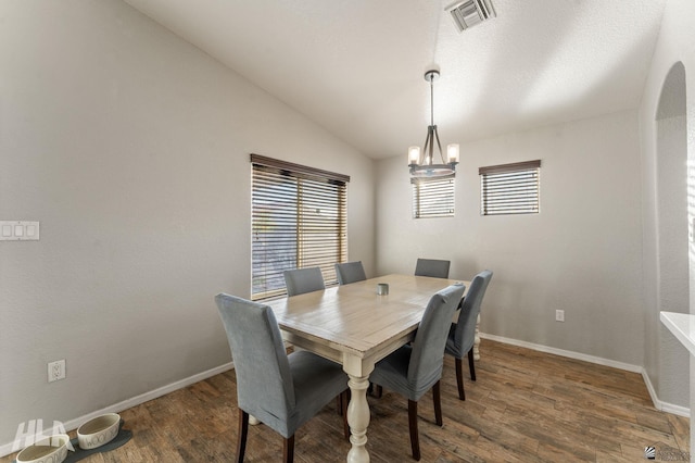 dining space featuring lofted ceiling, dark wood-type flooring, and a notable chandelier