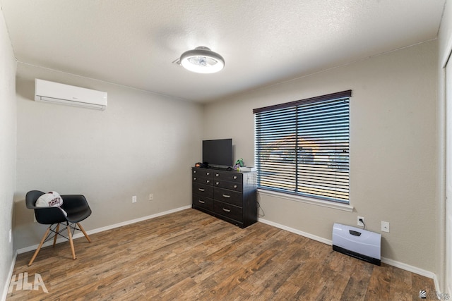 living area featuring dark hardwood / wood-style flooring, a wall unit AC, and a textured ceiling