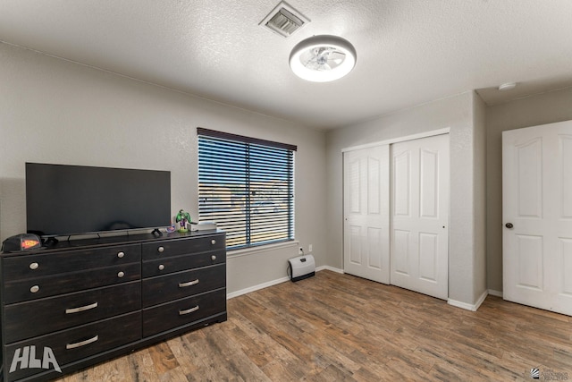 bedroom with hardwood / wood-style flooring, a textured ceiling, and a closet