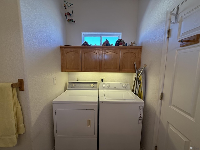 clothes washing area with cabinets and washer and clothes dryer