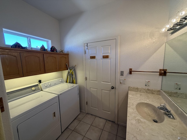 washroom with cabinets, light tile patterned floors, washing machine and dryer, and sink