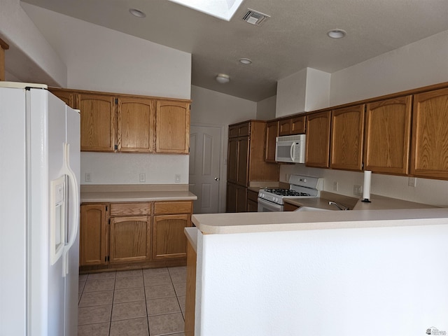 kitchen with kitchen peninsula, lofted ceiling, light tile patterned floors, and white appliances