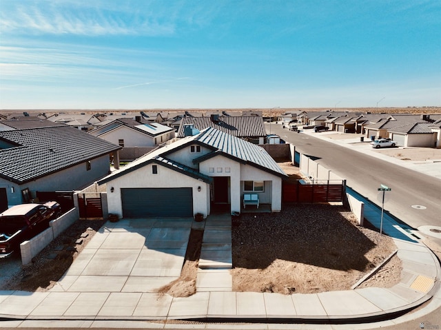 view of front facade with an attached garage, fence, driveway, a residential view, and stucco siding