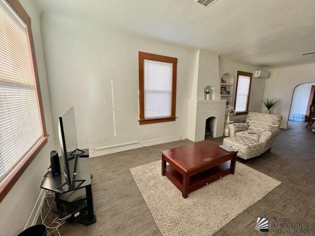 living room with built in features, a wall mounted AC, and a fireplace