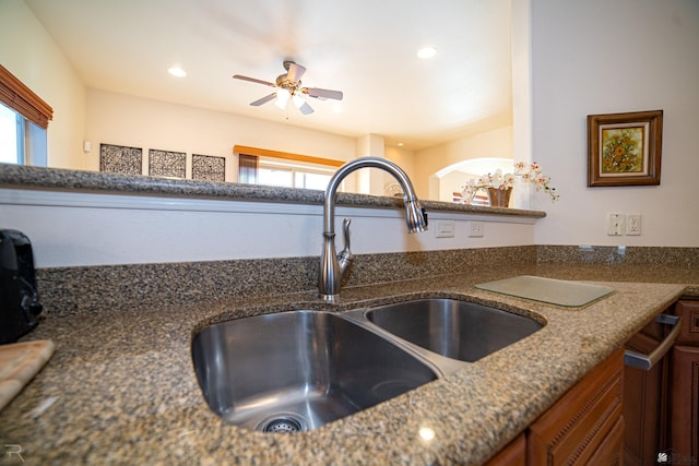 interior details with dark stone countertops, ceiling fan, and sink