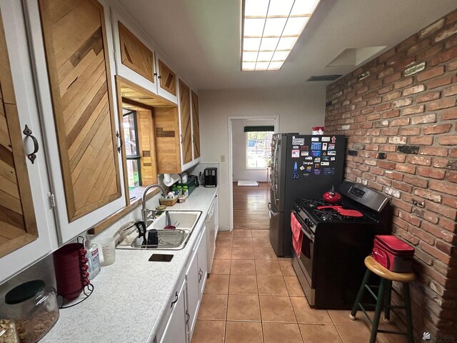 kitchen featuring light tile patterned floors, stainless steel appliances, white cabinetry, and sink