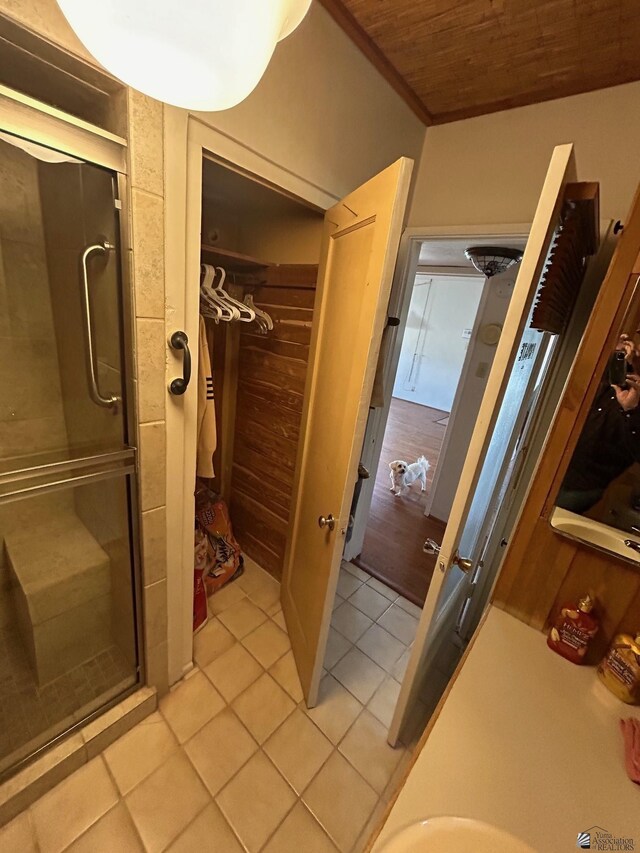 bathroom featuring tile patterned flooring, walk in shower, ornamental molding, and wood ceiling