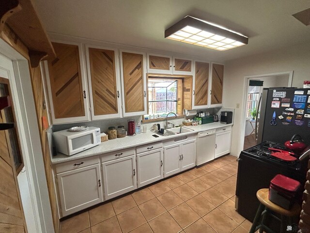 kitchen with sink, white cabinets, white appliances, and light tile patterned floors