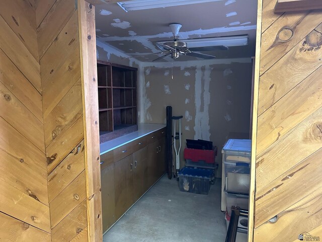 basement with wood walls and ceiling fan