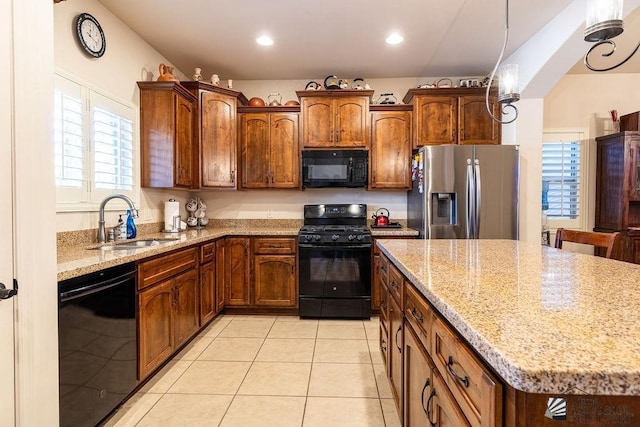 kitchen with light stone countertops, a center island, sink, light tile patterned flooring, and black appliances