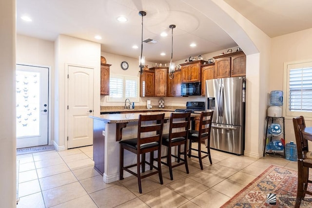 kitchen with a breakfast bar, a kitchen island, black appliances, and light tile patterned floors