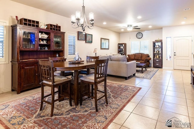 tiled dining space with ceiling fan with notable chandelier