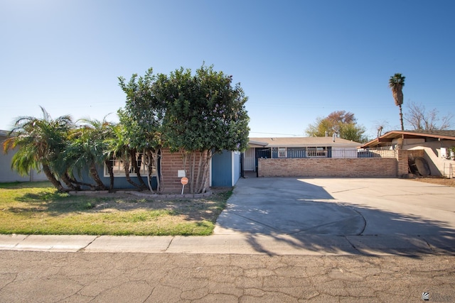 view of front of home featuring driveway, fence, and brick siding