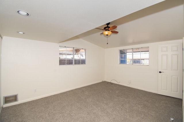 unfurnished room featuring baseboards, vaulted ceiling, visible vents, and dark colored carpet