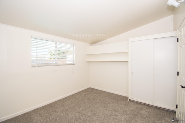 unfurnished bedroom featuring lofted ceiling, a closet, baseboards, and light colored carpet