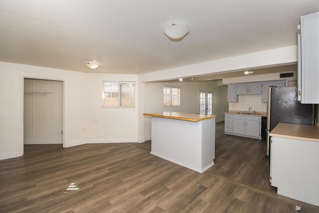 kitchen with gray cabinetry, a sink, a healthy amount of sunlight, a center island, and dark wood-style floors