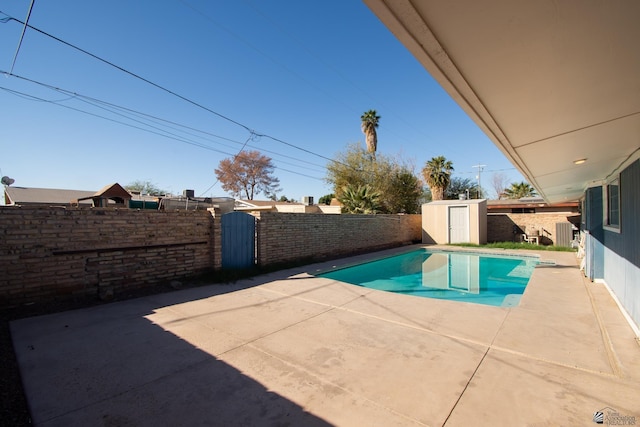 view of swimming pool with a fenced backyard, a storage shed, an outdoor structure, a fenced in pool, and a patio area