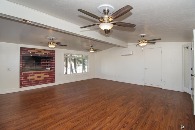 unfurnished living room with dark wood-style floors, a wall mounted air conditioner, a textured ceiling, and baseboards