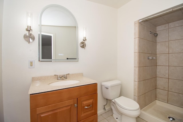 bathroom with tile patterned flooring, tiled shower, vanity, and toilet