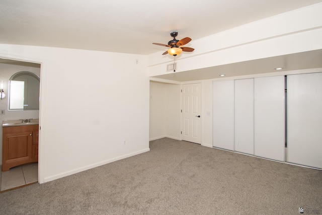 unfurnished bedroom featuring visible vents, light carpet, a sink, connected bathroom, and baseboards