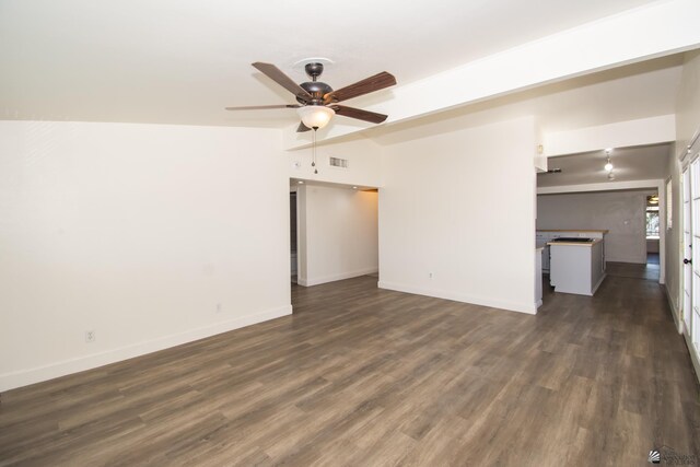 empty room featuring dark wood-style flooring, visible vents, and baseboards