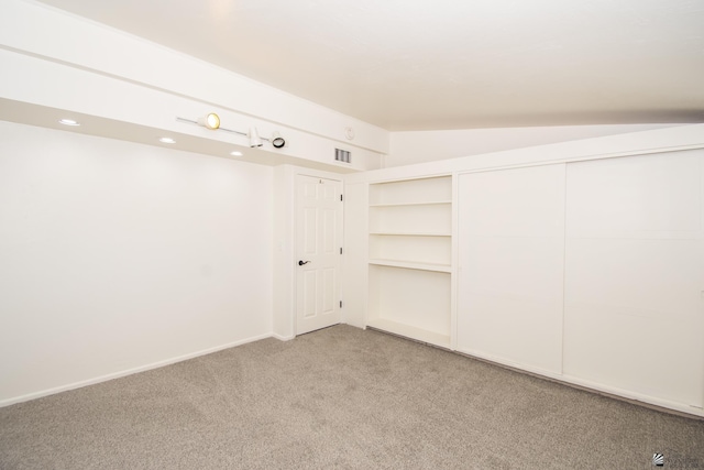 interior space featuring carpet, visible vents, lofted ceiling, and baseboards