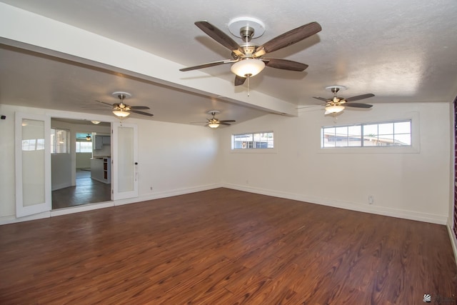 spare room with vaulted ceiling with beams, a textured ceiling, baseboards, and dark wood-style flooring