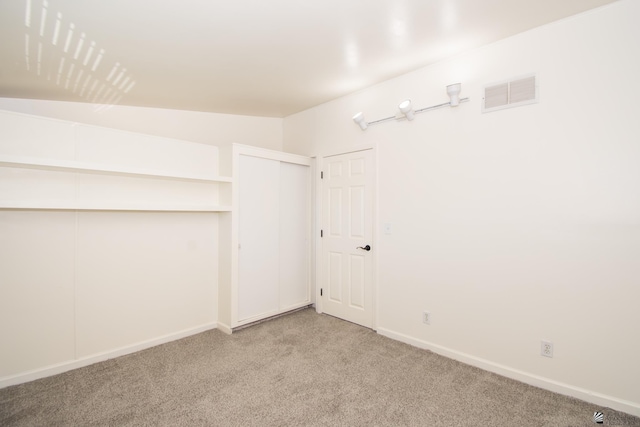 walk in closet with visible vents, vaulted ceiling, and light carpet