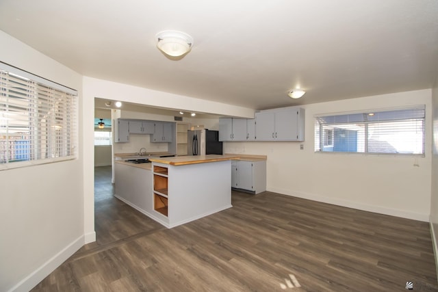 kitchen with baseboards, freestanding refrigerator, gray cabinets, open shelves, and wooden counters