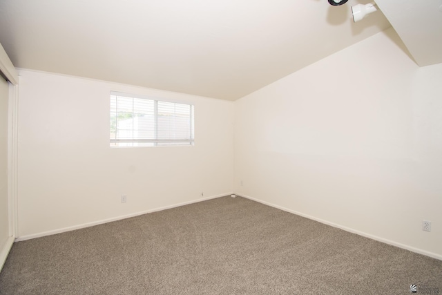 empty room featuring lofted ceiling, a ceiling fan, baseboards, and carpet flooring