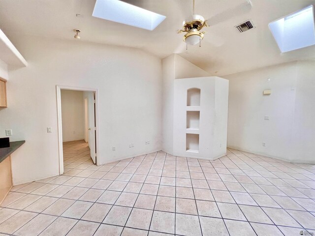 unfurnished living room featuring lofted ceiling with skylight, ceiling fan, and light tile patterned floors