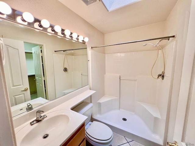 bathroom with toilet, tile patterned flooring, vanity, and walk in shower