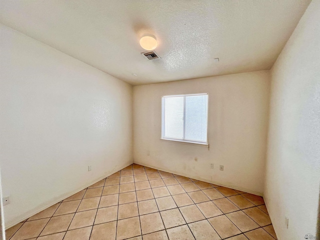 tiled empty room with a textured ceiling