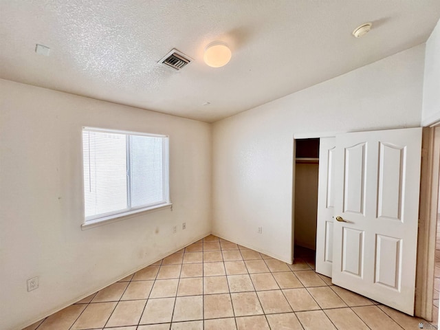 unfurnished bedroom featuring light tile patterned floors, a textured ceiling, and a closet