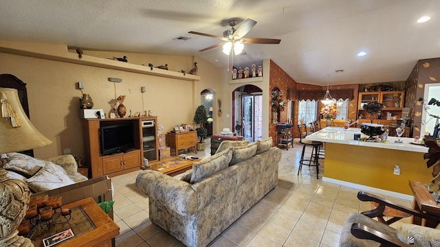 living area featuring lofted ceiling, light tile patterned flooring, arched walkways, and ceiling fan