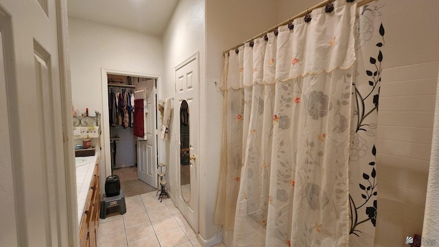 full bath with tile patterned flooring, a walk in closet, a shower with curtain, and vanity