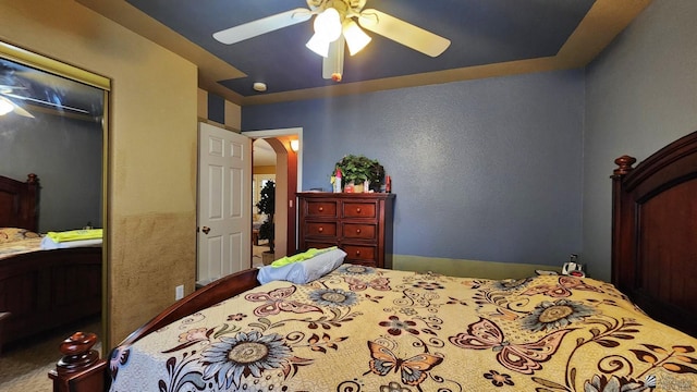 bedroom featuring arched walkways, a closet, and ceiling fan