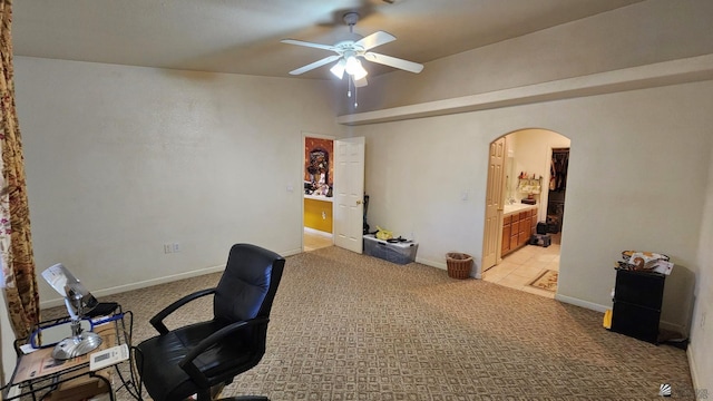 office space with baseboards, arched walkways, light colored carpet, and a ceiling fan